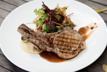 t-bone steak with vegetables on dark wooden background