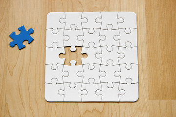 Letztes Teil eines weißen Puzzles auf Holuntergrund