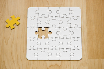 Letztes Teil eines weißen Puzzles auf Holuntergrund