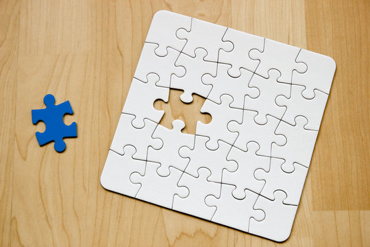 Letztes Teil eines wei&szlig;en Puzzles auf Holuntergrund