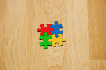 Vier zusammengesetzte Puzzleteile auf Holzuntergrund