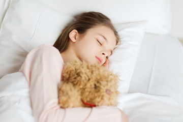 girl sleeping with teddy bear toy in bed at home