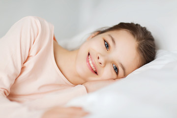 happy smiling girl lying awake in bed at home