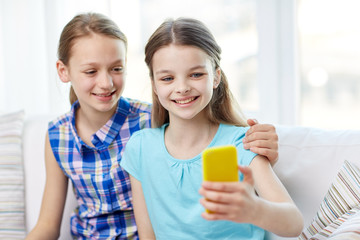 happy girls with smartphone taking selfie at home