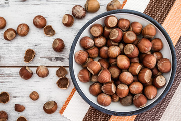 Hazelnuts in Enamel Bowl on White Wooden Table