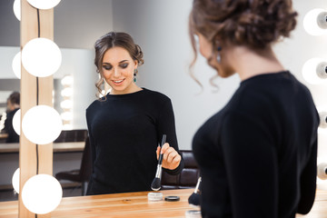 Smiling woman applying cosmetic with brush