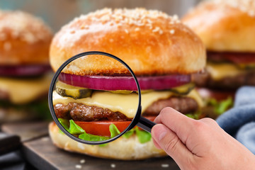 Magnifying glass examining burger  - 98095679