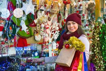Cheerful young woman choosing Christmas decoration at market