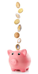 Pink piggy bank with coins falling into slot isolated on white.