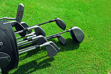 Golf bag with clubs on green field, close up