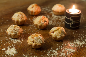 Seven salty muffins with sausage, cheese and sesame near candle on wood table.