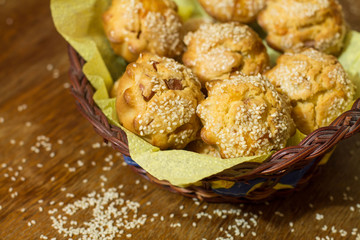 Salty muffins with sausage, cheese and sesame in basket on brown wood table.