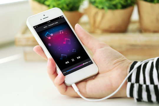 Music smartphone in female hand, on light background