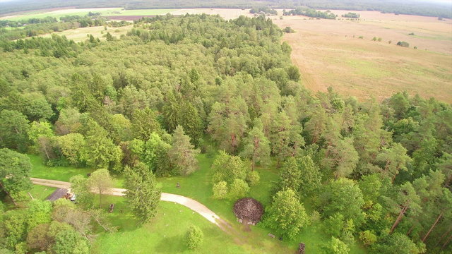The view from the sky of the greany hill of Emumagi. Green trees in the forest and the small huts and the large hayfield on the side