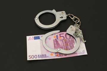 Handcuffs and money on black background