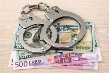 Handcuffs and money on wooden background