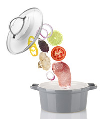 Fresh ingredients falling into a casserole pot isolated on white