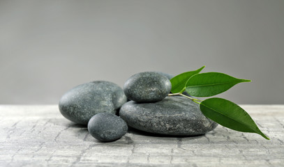 Pebbles with leaf on the table against grey background
