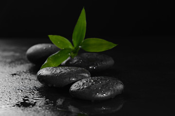 Fototapeta na wymiar Pebbles with bamboo leaf on black background