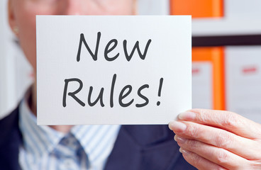 New Rules - Manager with sign and text in the office