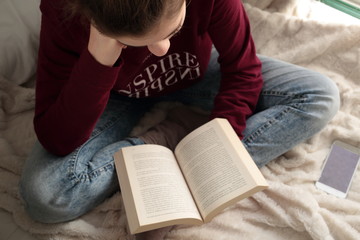 Fototapeta na wymiar Teenager reading a book in bed 