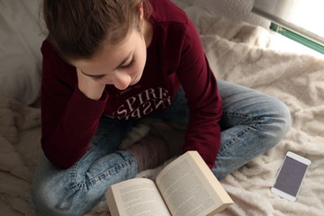 Teenager reading a book in bed
