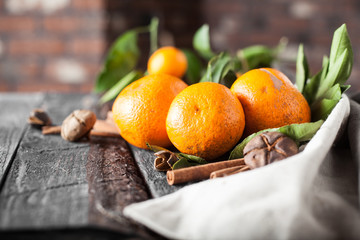 tangerines branch on a table with cinnamon and sachets