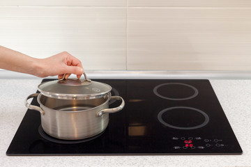 Woomen hand open a saucepan in modern kitchen with induction stove