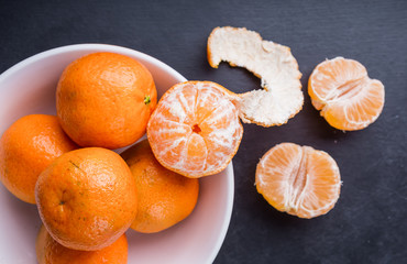 Organic mandarin oranges in white bowl on black table © aneta_gu