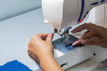 Woman is putting thread into her sewing machine