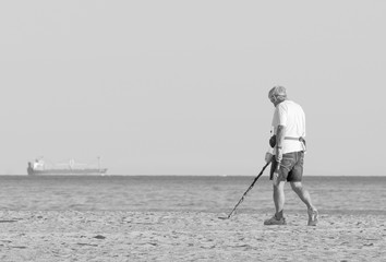 Man uses metal detector on a beach