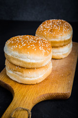 Buns with sesame for hamburger on a kitchen board