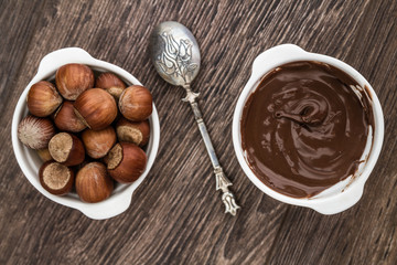 Chocolate Cream and Hazelnuts in White Bowls on Brown Wooden Tab
