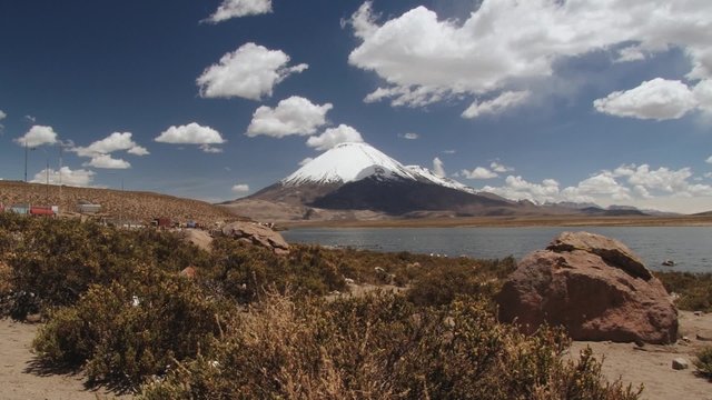 View to the Chungara lake and Parinacota volcano with trucks waiting in line for border control in Lauca Natioanl Park, Chile. 
