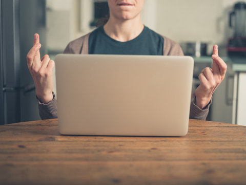 Woman crossing her fingers by laptop