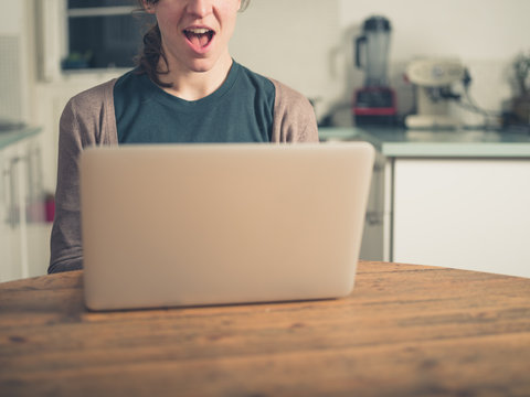 Excited woman with laptop in kitchen