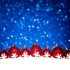 christmas red balls in snow on blue glitter background