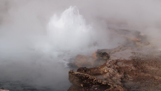 El Tatio geyser boils and produces steam at sunrise at the famous El Tatio geyser valley at 4320 meters above sea level,  Chile.