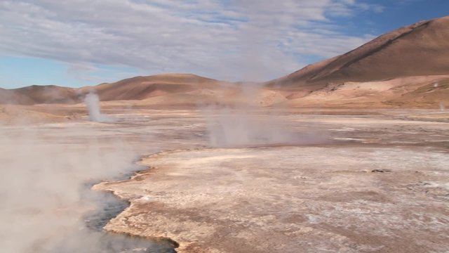 Spring with natural thermal water produces hot steam at sunrise at the famous El Tatio geyser valley at 4320 meters above sea level, Chile.