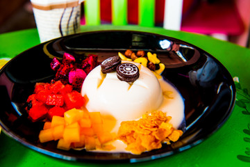 Cold tofu pudding with fruit and dessert on black dish