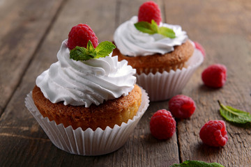 Delicious cupcakes with berries and fresh mint on wooden table close up