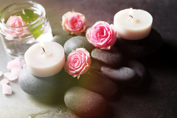 Fototapeta na wymiar Spa composition of candles, stones and flowers, on grey background