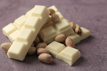 White chocolate pieces with nuts on color wooden background