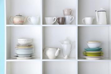 Different clean dishes on wooden shelves