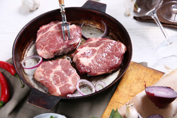 Marbled beef steak on pan and spices on color wooden background