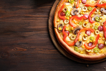 Delicious pizza with vegetables and meat on wooden table
