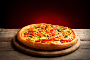 Delicious pizza with vegetables on dark red background