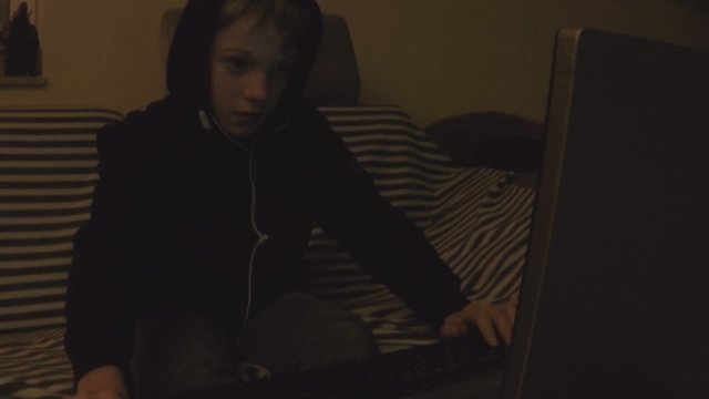 Kind spielt am PC in der Dunkelheit der Nacht