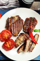 Roasted beef fillet and grilled vegetables on plate, on wooden background