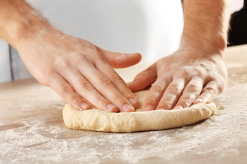Hands kneading dough for pizza on the wooden table, close-up